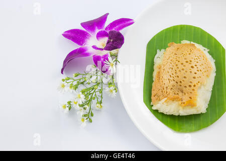 Riso al vapore con crema pasticcera su foglie di banano e piatto con fiori di orchidea, dolci di riso appiccicoso, Thai dessert, originale Foto Stock