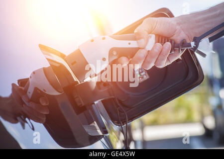 Immagine a colori di una mano di un uomo la preparazione per caricare un auto elettrica. Foto Stock