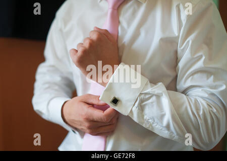 L'uomo mette sulla sua maglietta polsini mattina groom accessori Foto Stock