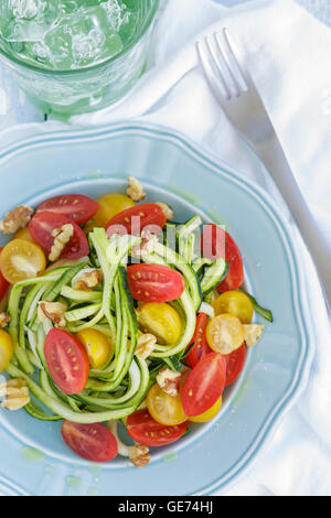 Tagliatelle di zucchine con pomodori e noci si lancia in olio di oliva Foto Stock