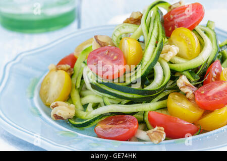 Tagliatelle di zucchine con pomodori e noci si lancia in olio di oliva Foto Stock