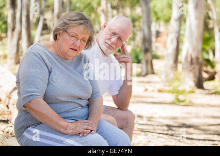 Molto turbato Senior donna si siede con il marito interessati all'esterno. Foto Stock