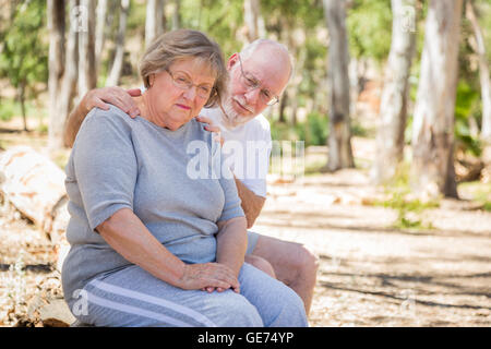 Molto turbato Senior donna si siede con il marito interessati all'esterno. Foto Stock