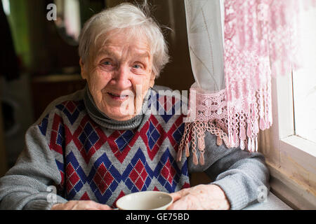 Felice anziani ritratto di donna seduta al tavolo in il maglione. Foto Stock