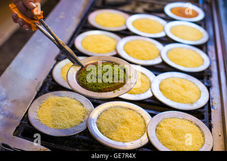 Chef di cucina turca tradizionale delizioso dessert Kunefe e mostrano Kunefe cotti con polvere di pistacchio closeup Foto Stock