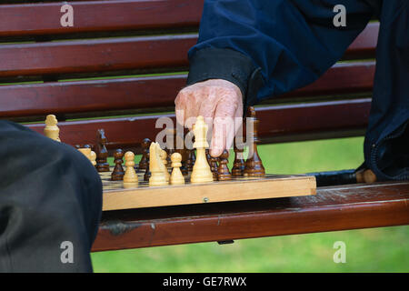 Amici di vecchia data e tempo libero. Due anziani divertirsi e giocare a scacchi gioco al parco sulla panchina. Foto Stock