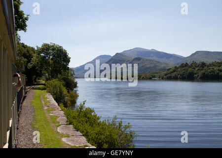 La vista di Snowdon dal vapore di bolina treno sul Llanberis Lake Railway su un luminoso cielo blu giornata d'estate Foto Stock