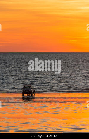 Una trazione a quattro ruote motrici veicolo parcheggiato sul cavo spiaggia al tramonto, Broome, Kimberley, Australia occidentale, Australia Foto Stock