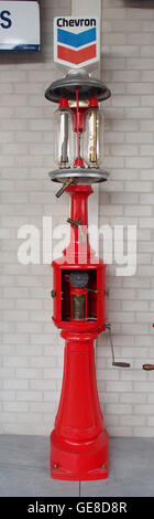 Questa immagine raffigura una vecchia pompa a gas Chevron, che riflette il design e il marchio Chevron della metà del XX secolo. La pompa a gas rappresenta l'era vintage delle stazioni di servizio, catturando l'estetica e il marchio del tempo. Foto Stock