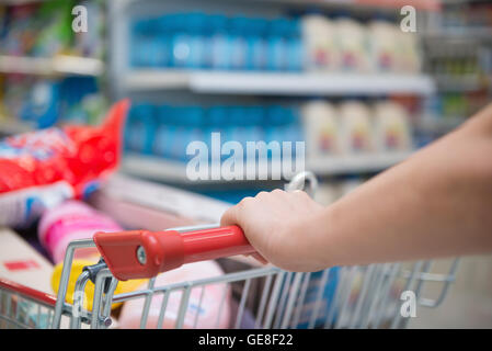 Lady shopping con un pieno riempito il carrello in un supermercato Foto Stock