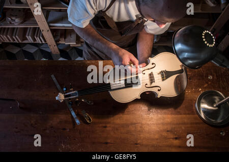 Liutaio regolazione del suono post di un violino non verniciate nel suo laboratorio Foto Stock