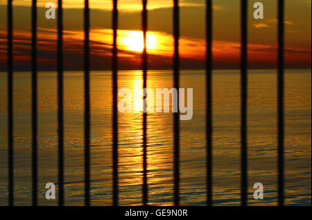 Il tramonto in serata presso il Mar Baltico dietro le barre Foto Stock