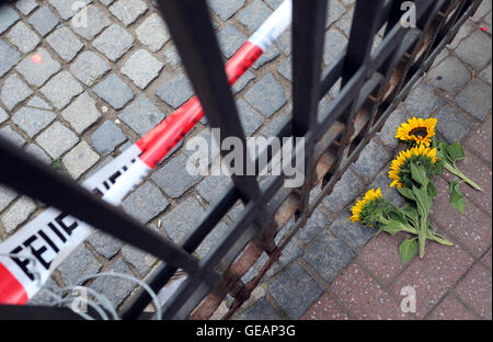 Ansbach, Germania. Xxv Luglio, 2016. Girasoli giacciono da un cancello chiuso dietro il nastro di polizia vicino la scena del crimine nella città vecchia di Ansbach, Germania, 25 luglio 2016. 15 persone sono rimaste ferite in un presunto di islamisti-attacco motivato il 24 luglio 2016. Il sospettato colpevole, un 27-anno-vecchio rifugiato dalla Siria, è stato ucciso in un attacco. Foto: KARL-JOSEF HILDENBRAND/dpa/Alamy Live News Foto Stock