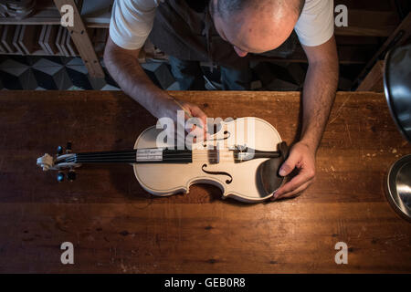 Liutaio regolazione del suono post di un violino non verniciate nel suo laboratorio Foto Stock