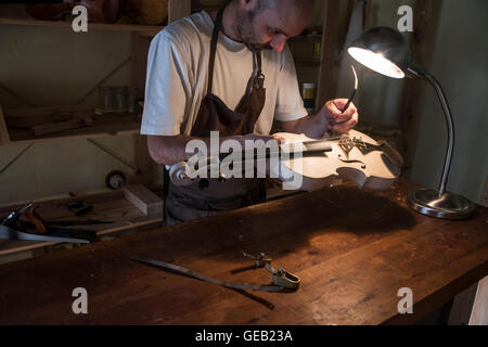 Liutaio regolazione del suono post di un violino nel suo laboratorio Foto Stock