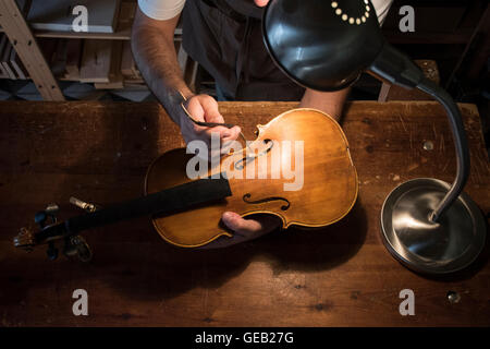 Liutaio regolazione del suono post di un violino nel suo laboratorio Foto Stock