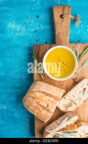 Spuntini mediterranei set. Olio d'oliva, erbe e fette di ciabatta pane rustico di legno Foto Stock