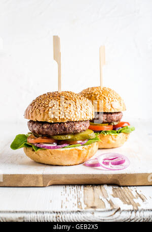 Fresca hamburger fatti in casa in legno che serve la scheda con anelli di cipolla. Foto Stock