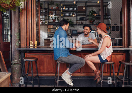 Un gruppo di giovani amici seduti e parlare in un bar. Giovani uomini e donne riuniti in una caffetteria. Foto Stock