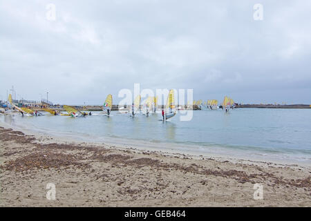 Gli appassionati di windsurf in giallo le vele a decollare in un windsurf internazionale della concorrenza in condizioni di tempo piovoso in Playa de Palma di Maiorca. Foto Stock