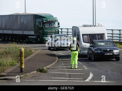 Un funzionario di polizia dirigere il traffico sulla A2 approccio al Porto di Dover nel Kent, come i ritardi per i viaggiatori diretti verso Dover hanno alleviato ma gli automobilisti sono stati avvertiti di aspettarsi alcune interruzioni per le settimane a venire. Foto Stock