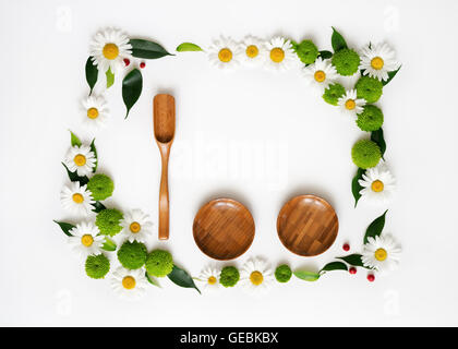 Cucchiaio di legno, piastre e lo spazio per il tuo testo o prodotto con decorazione di crisantemo fiori e foglie di ficus su bianco backg Foto Stock