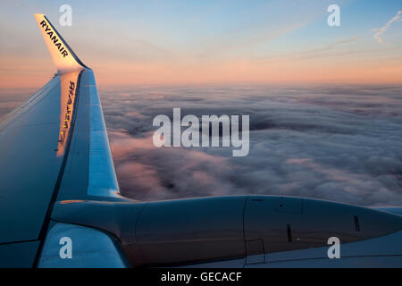 Tramonto dalle nubi attraverso l'aletta di un aereo Ryanair che vola da Liverpool a Riga su un volo di linea. Foto Stock