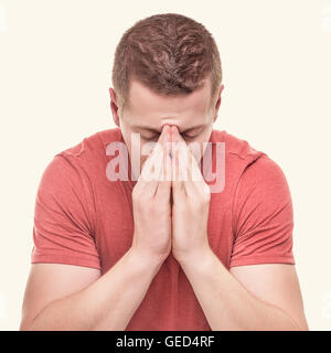 Giovane uomo è pregare concentrato su sfondo bianco. Tonica foto. Foto Stock