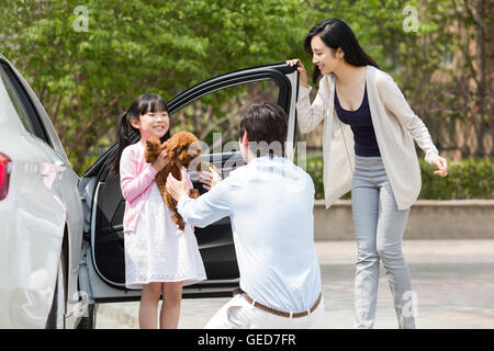 Giovane famiglia cinese di ottenere al di fuori della vettura con il loro cane Foto Stock