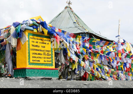 Segno e bandiere di preghiera accanto alla strada sterrata oltre il mountain pass, Tanglangla Pass, Manali - Leh Road, Himachal Pradesh, India, Foto Stock