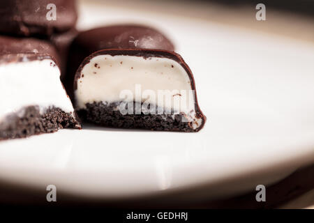Gelato alla vaniglia bomboni ricoperto di cioccolato per deserto su una piastra bianca. Foto Stock