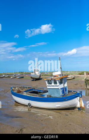 Piccole barche da pesca spiaggiata a bassa marea nel fango a Brancaster Staithe, Norfolk, Inghilterra, Regno Unito Foto Stock