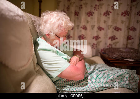 La vecchiaia pensionato addormentato veloce sul divano nel soggiorno, England, Regno Unito Foto Stock