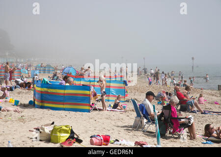 Ora legale britannica, vacanzieri godere le calde temperature on Avon Beach in Dorset, sebbene la foschia marina oscura il sole, REGNO UNITO Foto Stock