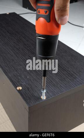 Le viti del lavoratore in un arredamento in legno con un cacciavite Foto Stock