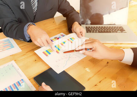 Partner commerciali in tuta discutendo documenti e idee ad una riunione di affari concetto, soft focus, tono vintage Foto Stock