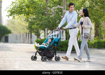 Giovani cinesi giovane facendo una passeggiata con il loro bambino nella PRAM Foto Stock