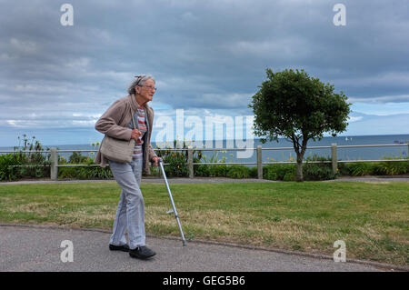 Una vecchia signora camminando lungo il lungomare di Falmouth, Cornwall Foto Stock