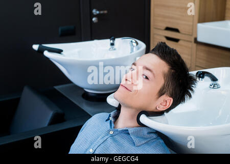 Vista di profilo di un giovane uomo di prepararsi per i suoi capelli lavati Foto Stock