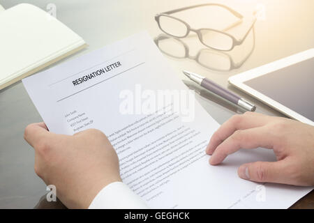 Imprenditore rivedere le sue dimissioni lettera sulla sua scrivania prima di inviare a suo boss per abbandonare il suo lavoro. Lettera di dimissioni informazioni Foto Stock