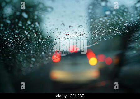 Le gocce di pioggia sul parabrezza in vetro con sfocate sullo sfondo del traffico Foto Stock