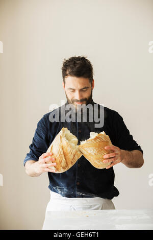 Baker tenendo due appena sfornato pagnotte di pane. Foto Stock