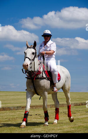 Femmina di giocatore di polo su un cavallo bianco e in abito bianco montato subito prima che il gioco Foto Stock