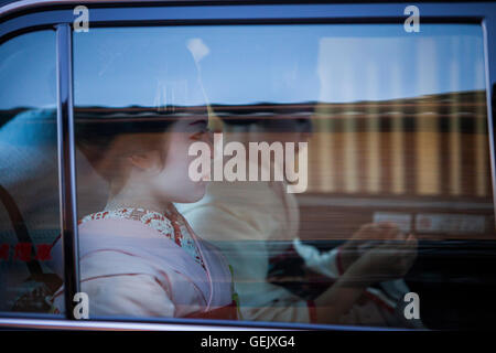 Maiko si (geisha apprendista) in taxi. Hanamikoji dori street.Geisha il quartiere di Gion.Kyoto. Kansai, Giappone. Foto Stock