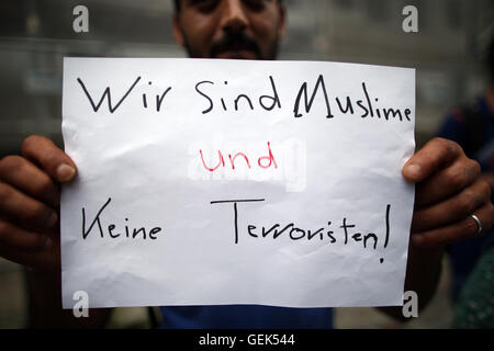 Ansbach, Germania. 26 Luglio, 2016. Un rifugiati dalla Siria sorge nei pressi del sito di attacco e sorregge un cartello con la scritta "siamo musulmani e non terroristi" in Ansbach, Germania, 26 luglio 2016. 15 persone sono rimaste ferite in un islamista sospetti motivati attaccare il 24 luglio 2016. Il sospettato colpevole, un 27-anno-vecchio rifugiato dalla Siria, è stato ucciso nell'esplosione. Foto: DANIEL KARMANN/dpa/Alamy Live News Foto Stock