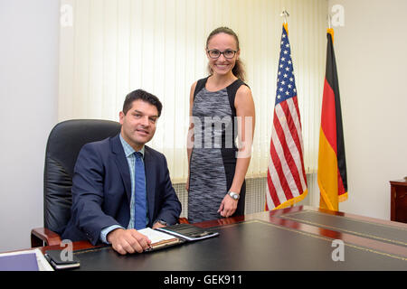 Kaiserslautern, Germania. 1 Luglio, 2016. Roberto da Costa, direttore dell'ufficio, e co-lavoratore Barbara Coe in posa davanti al tedesco e il US-bandiera americana al tedesco-americana Ufficio comunitario a Kaiserslautern, in Germania, 1 luglio 2016. Foto: OLIVER DIETZE/dpa/Alamy Live News Foto Stock