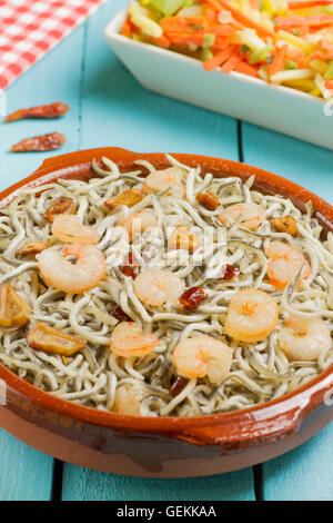 Surimi anguille con gamberetti, aglio e pepe in un tradizionale piatto di terracotta e le verdure su una ciotola bianco Foto Stock