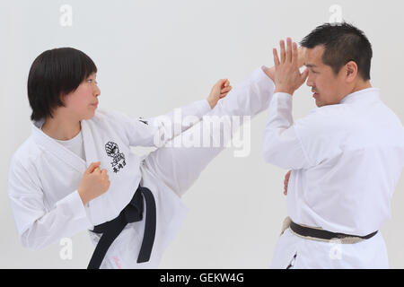 Ragazzo giapponese nel karate uniforme di formazione con docente su sfondo bianco Foto Stock