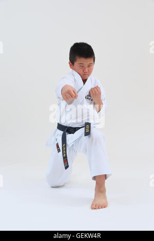 Ragazzo giapponese nel karate uniforme su sfondo bianco Foto Stock