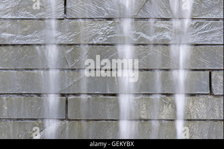 Cascata di seta a cascata verso il basso di un muro di pietra Foto Stock